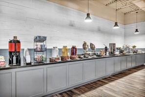 A long counter with various food and drink items, including coffee machines and condiments.