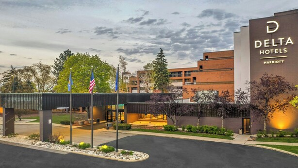 A Delta Hotels Marriott building with a modern design, featuring a prominent entrance and a landscaped area in front.