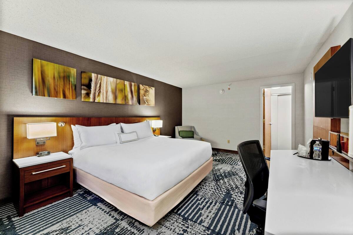 Habitación de hotel con cama, mesitas de noche, escritorio y televisor de pantalla plana.
