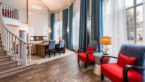A modern hotel room with a staircase, a dining area, and a seating area with red and blue furniture. - Best Western Plus Regency Inn & Conference Centre (Abbotsford)