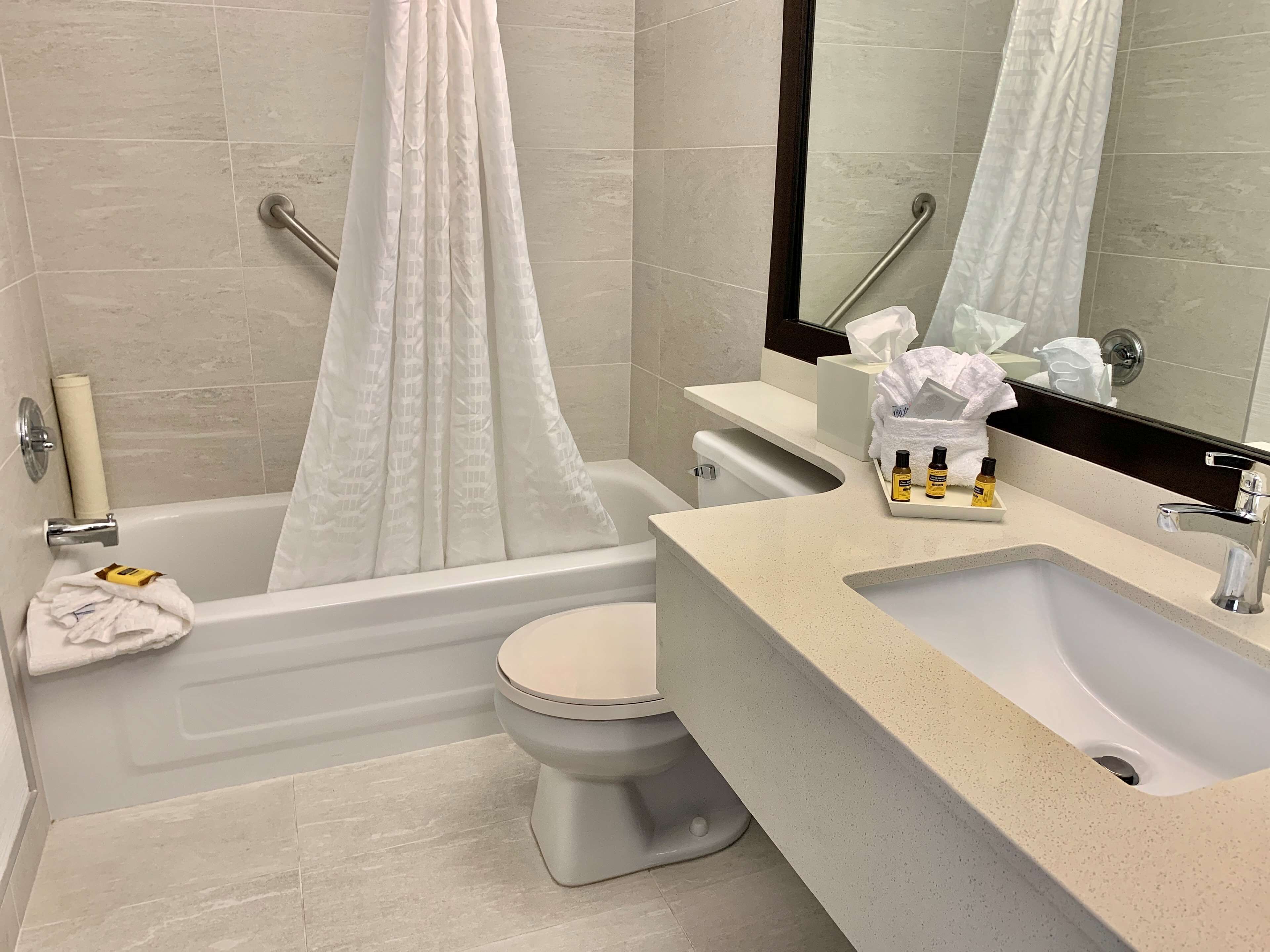 A bathroom with a bathtub, toilet, sink, and a mirror.