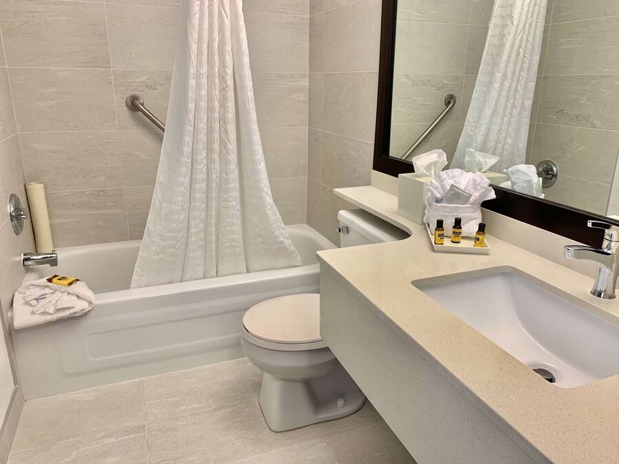 A bathroom with a bathtub, toilet, sink, and a mirror.