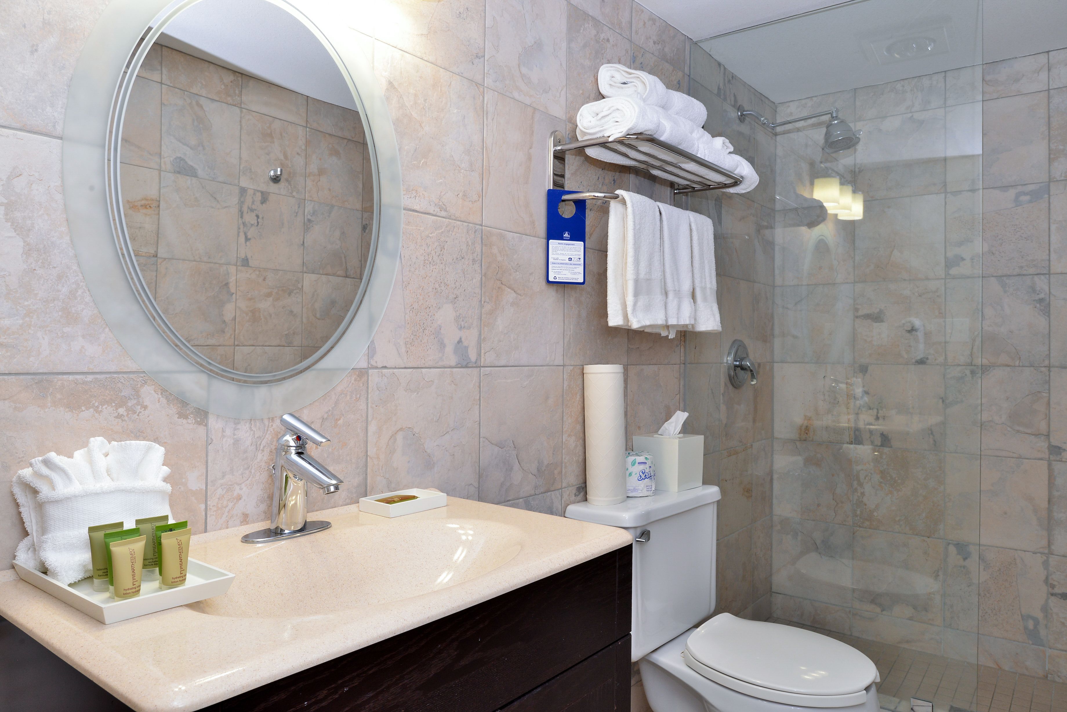 Een badkamer met een wastafel, spiegel, handdoekhouder en douche.