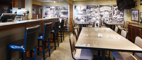 A restaurant with a long table, chairs, and a bar area.