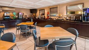 A restaurant with multiple tables and chairs, a bar area with various food and drink items, and a television mounted on the wall. - Best Western Plus Regency Inn & Conference Centre (Abbotsford)