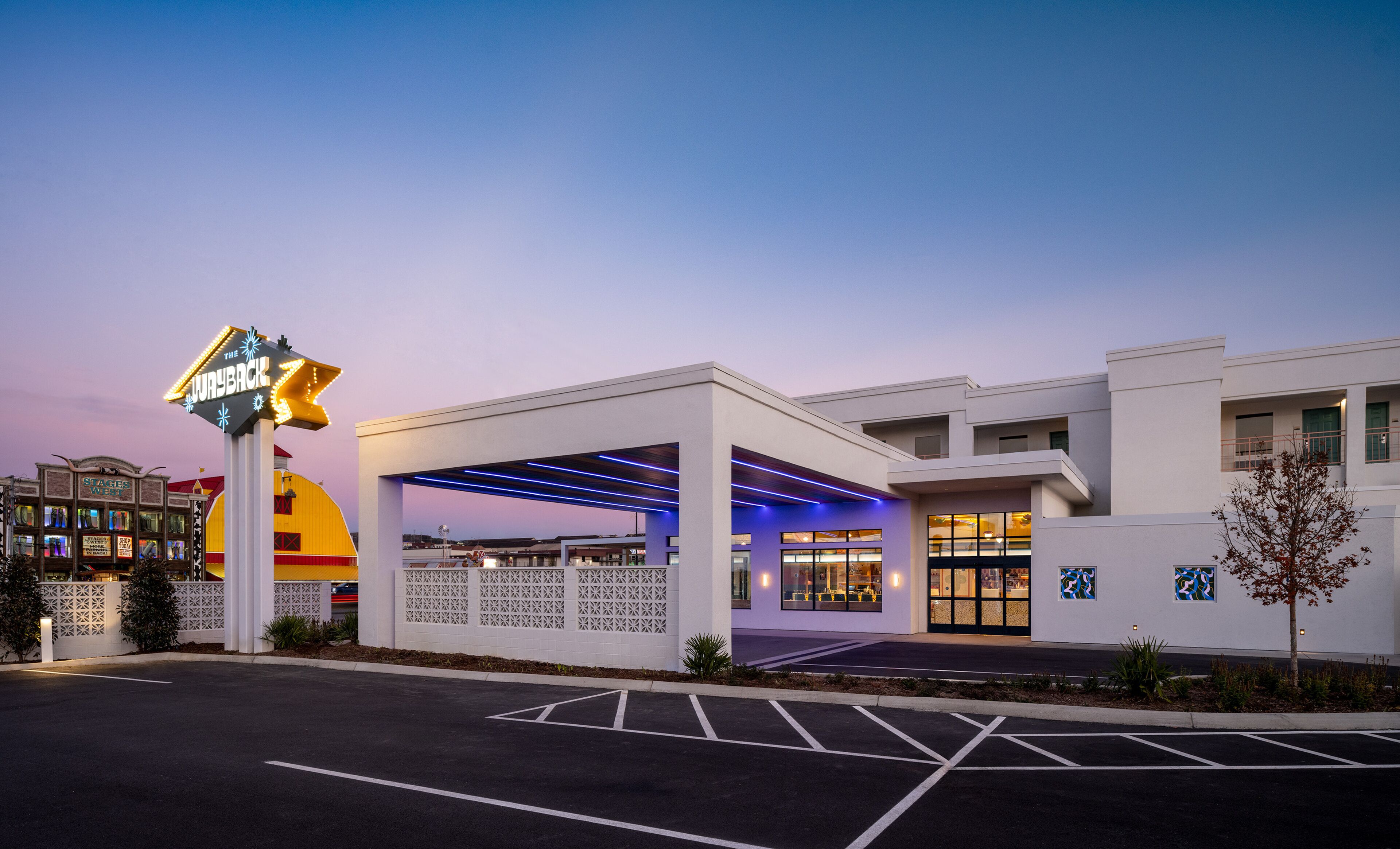 A hotel with a modern design, featuring a covered outdoor area and a prominent sign.