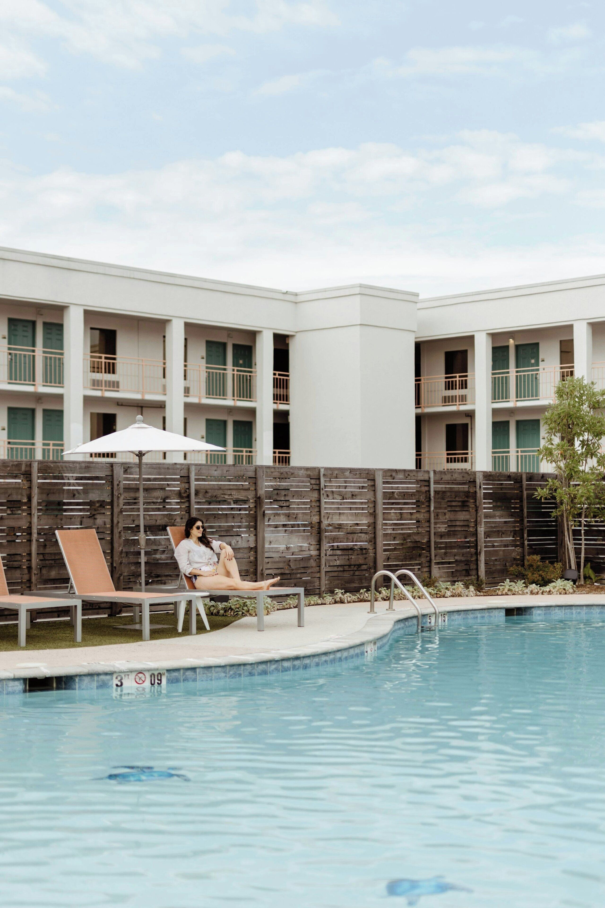 A swimming pool with lounge chairs and a person relaxing.