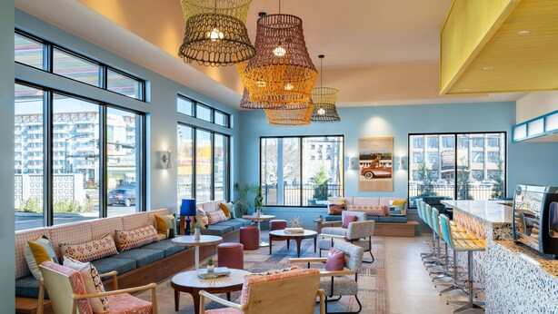 Ein moderner Lounge-Bereich mit Sitzgelegenheiten, einer Bar und großen Fenstern mit Blick auf die Stadt.