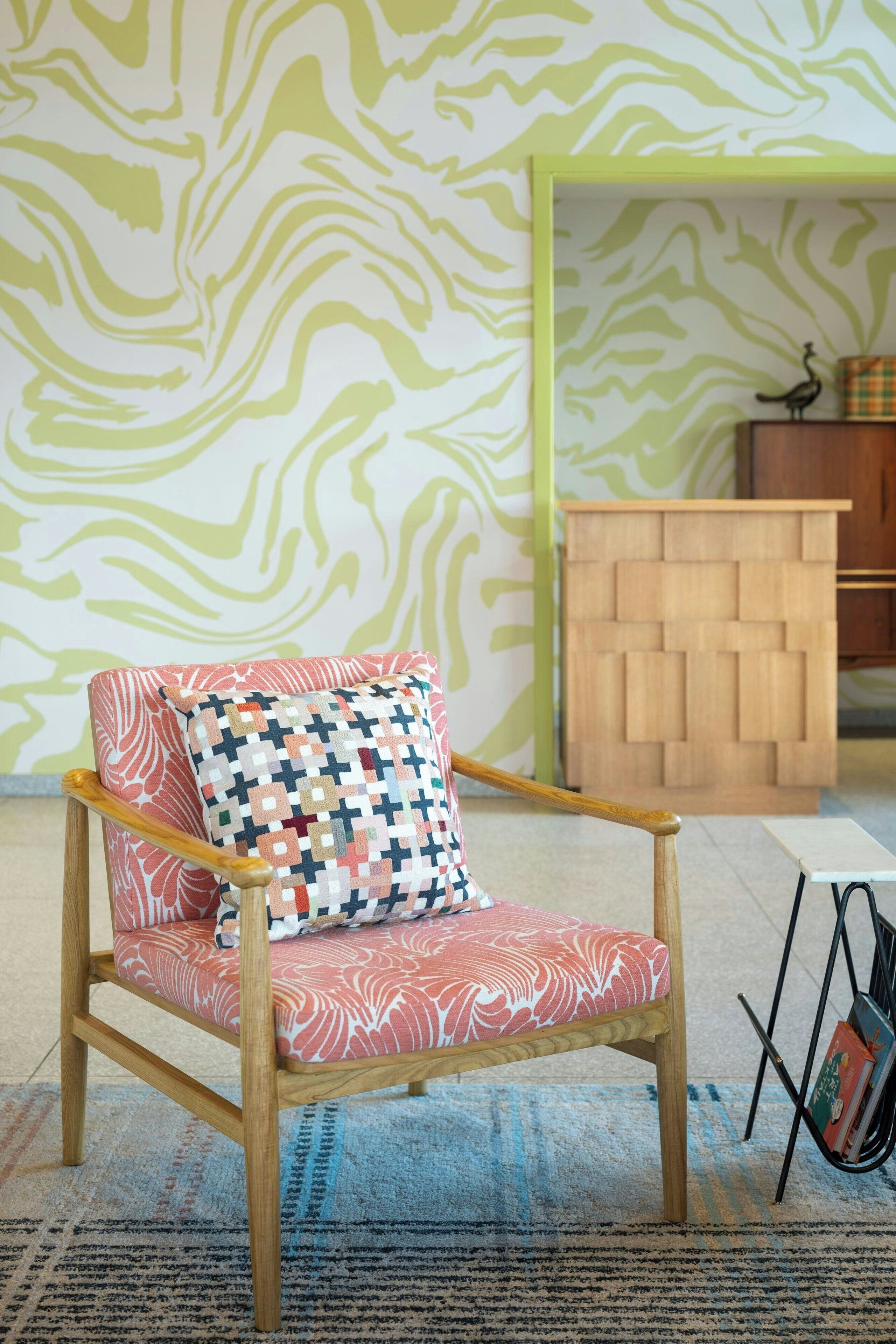 Un fauteuil en bois avec un coussin à motifs, un meuble en bois et un tapis à motifs.