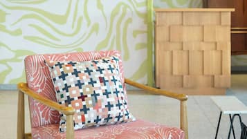 Un fauteuil en bois avec un coussin à motifs, un meuble en bois et un tapis à motifs.
