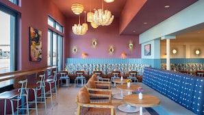 Ein modernes Restaurant-Interieur mit hohen Decken, besonderen Kronleuchtern und einem lebendigen Farbkonzept.