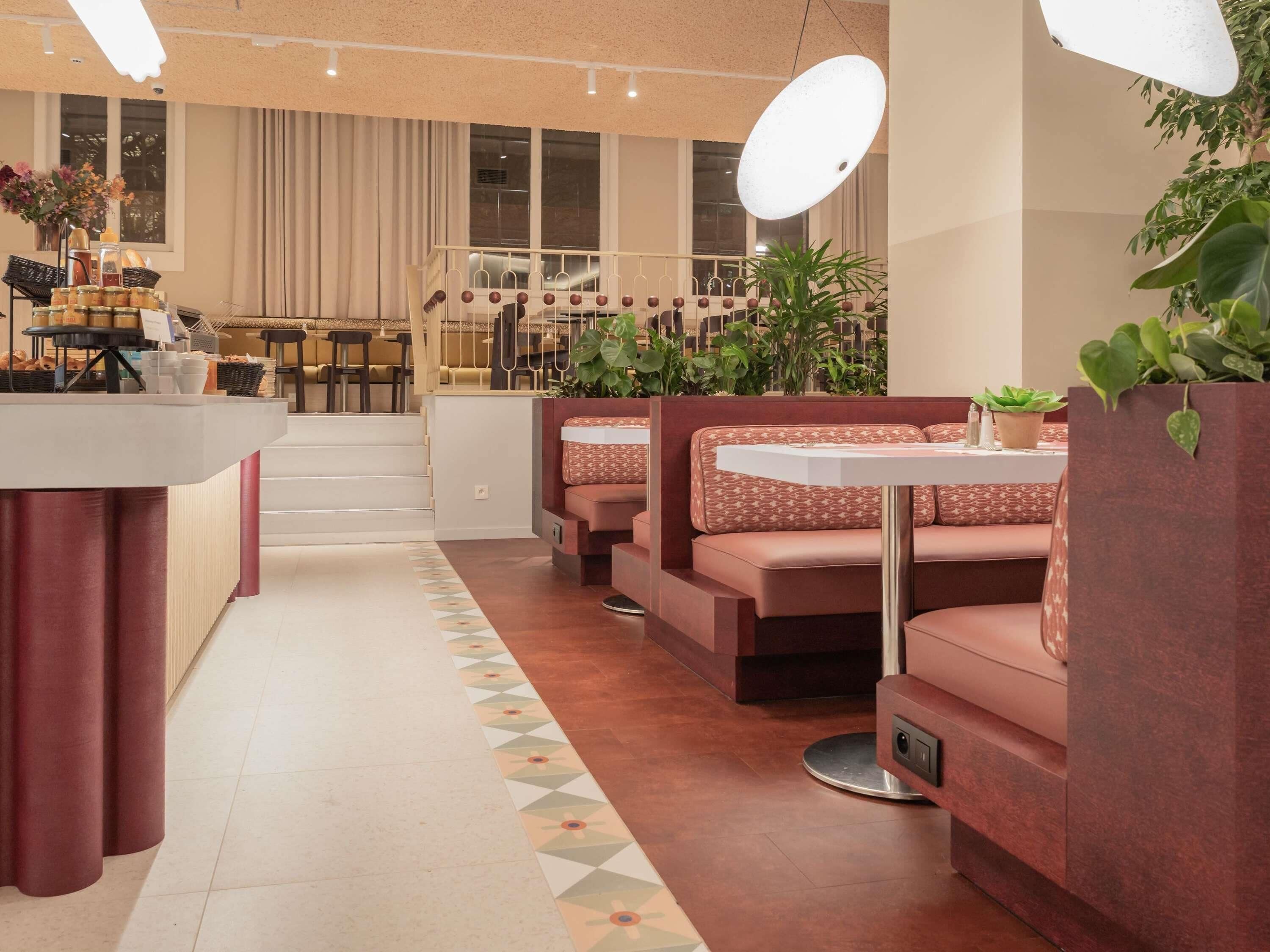 Un restaurante con mostrador, zona de mesas y una escalera que sube a un nivel superior.