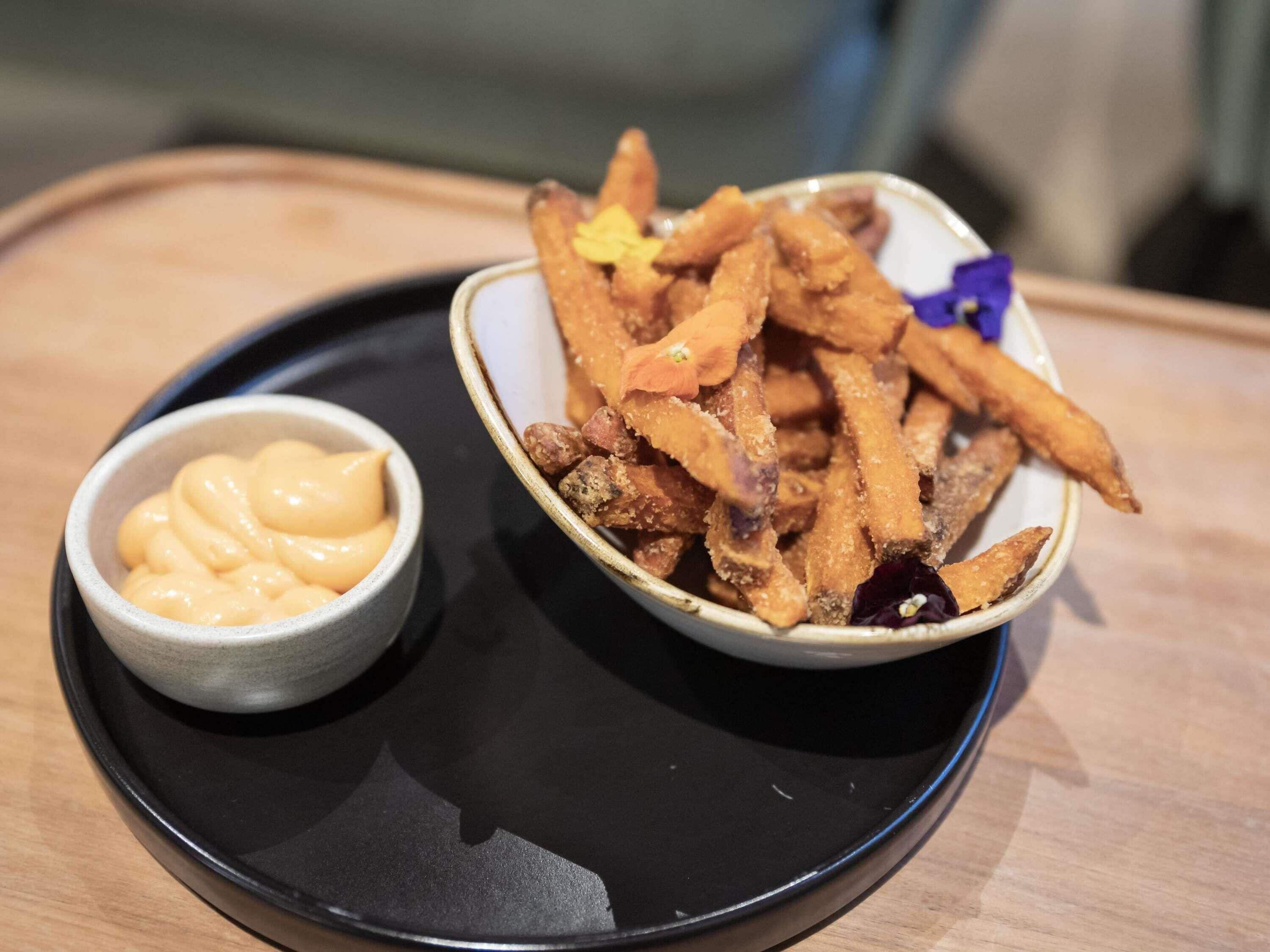 A plate with fries and a small bowl of sauce.