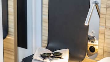 Un espace salon moderne et compact, doté d’une station de recharge intégrée et d’une petite table sur laquelle sont posés un livre et des lunettes de soleil.
