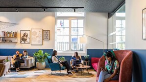 A modern lounge area with a herringbone wood floor, comfortable seating, and large windows providing natural light. - Novotel Brussels off Grand'Place (Brussels)