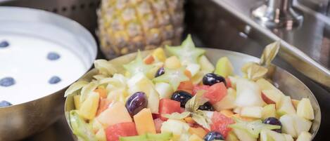 A fruit salad with various fruits and a pineapple in the background.