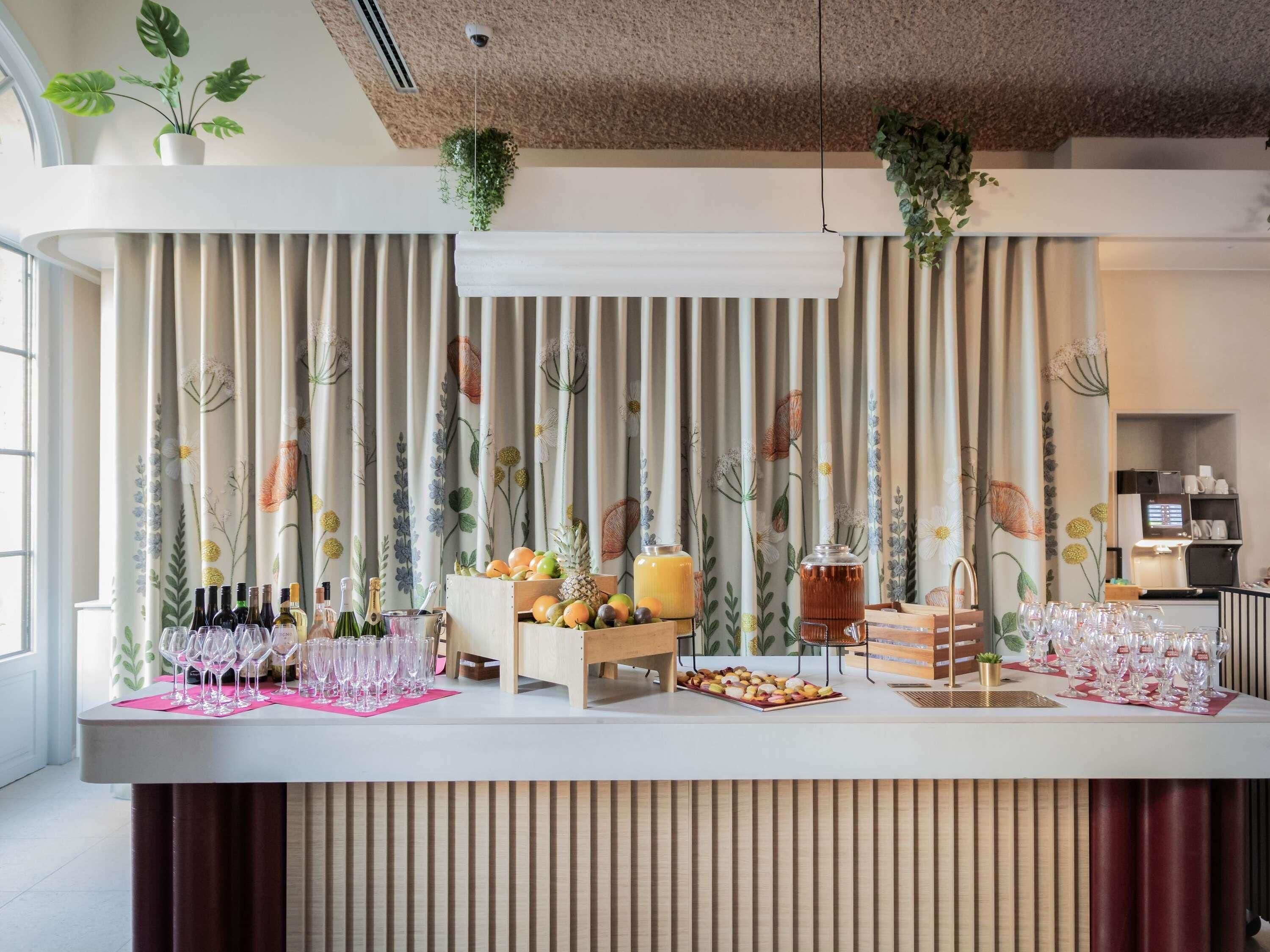 Zona de bar con mostrador, botellas, vasos, frutas y una máquina de café.