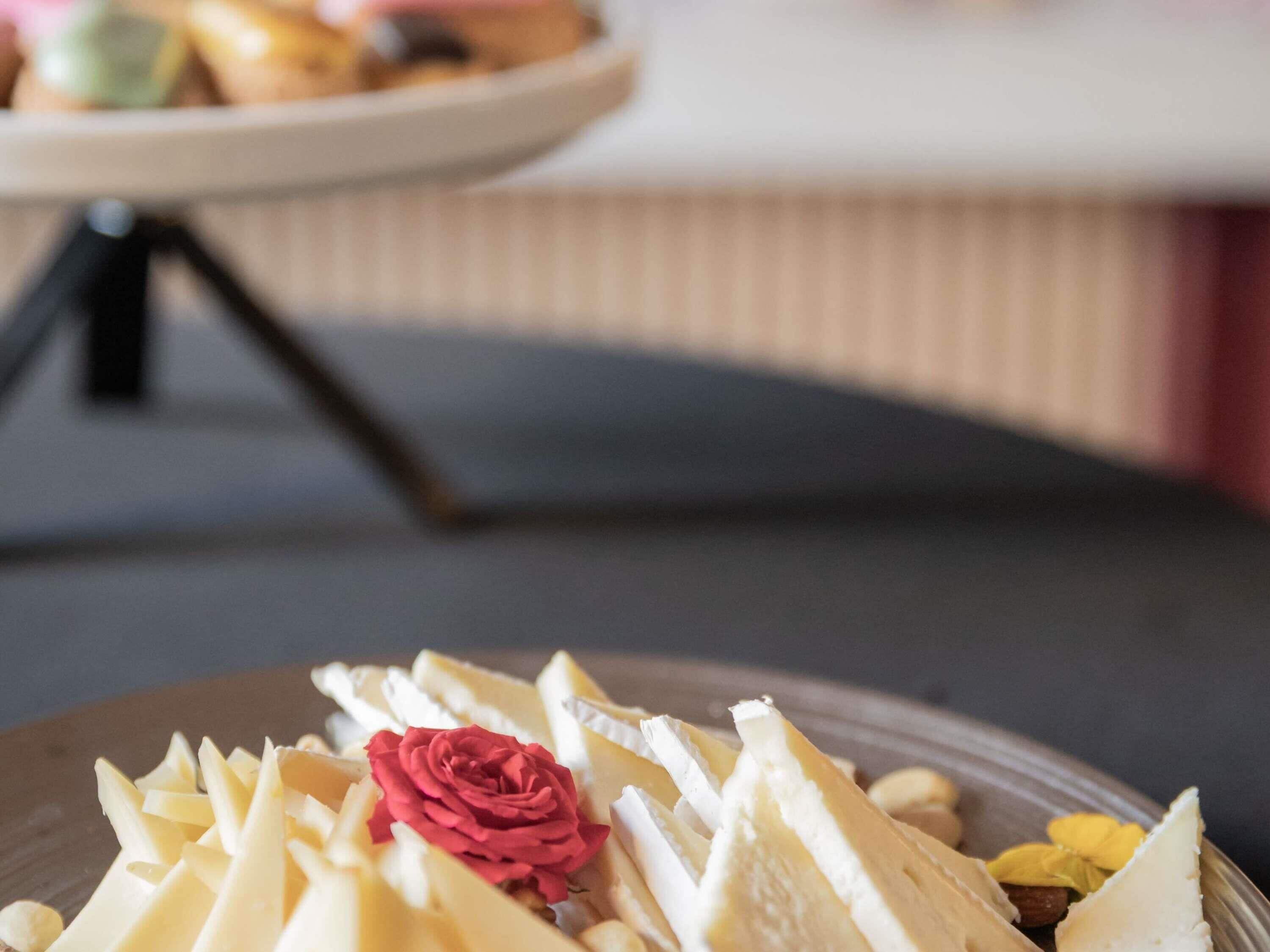 Un plato de queso con una rosa roja decorativa.