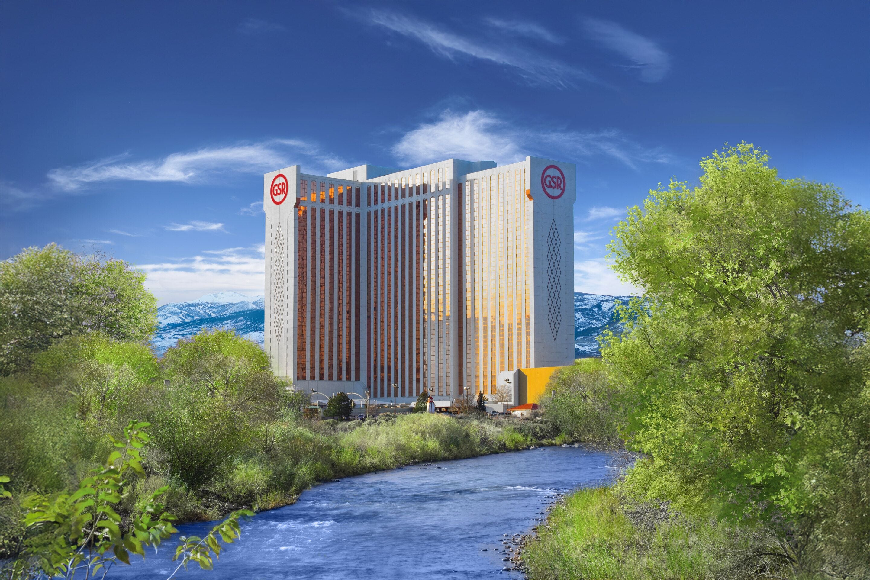 Een modern hotel met een opvallend GSR logo, omringd door weelderige begroeiing en een rivier.