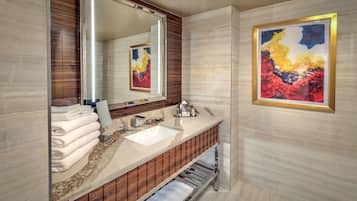Un baño moderno con un espejo grande, un lavamanos blanco, tocador de madera y un cuadro abstracto enmarcado en la pared.