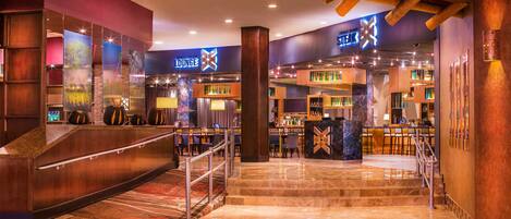 A modern hotel lobby with a bar area, a staircase, and a lounge.