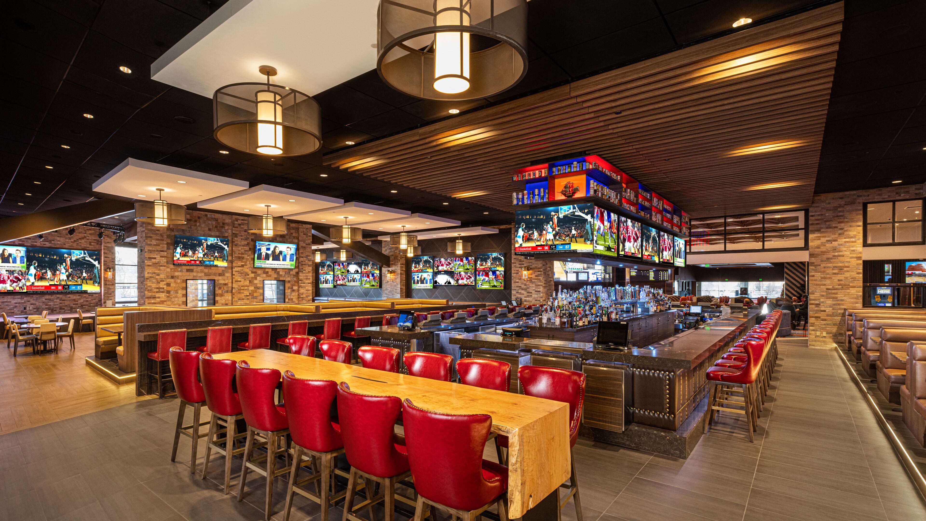 A bar area with multiple seating options, including red chairs and wooden tables.