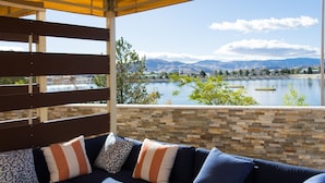 Un espacio de estar al aire libre con techo y vistas a un lago y montañas.