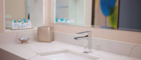 A bathroom with a white marble sink, a modern faucet, and a mirror reflecting a bathroom setting.