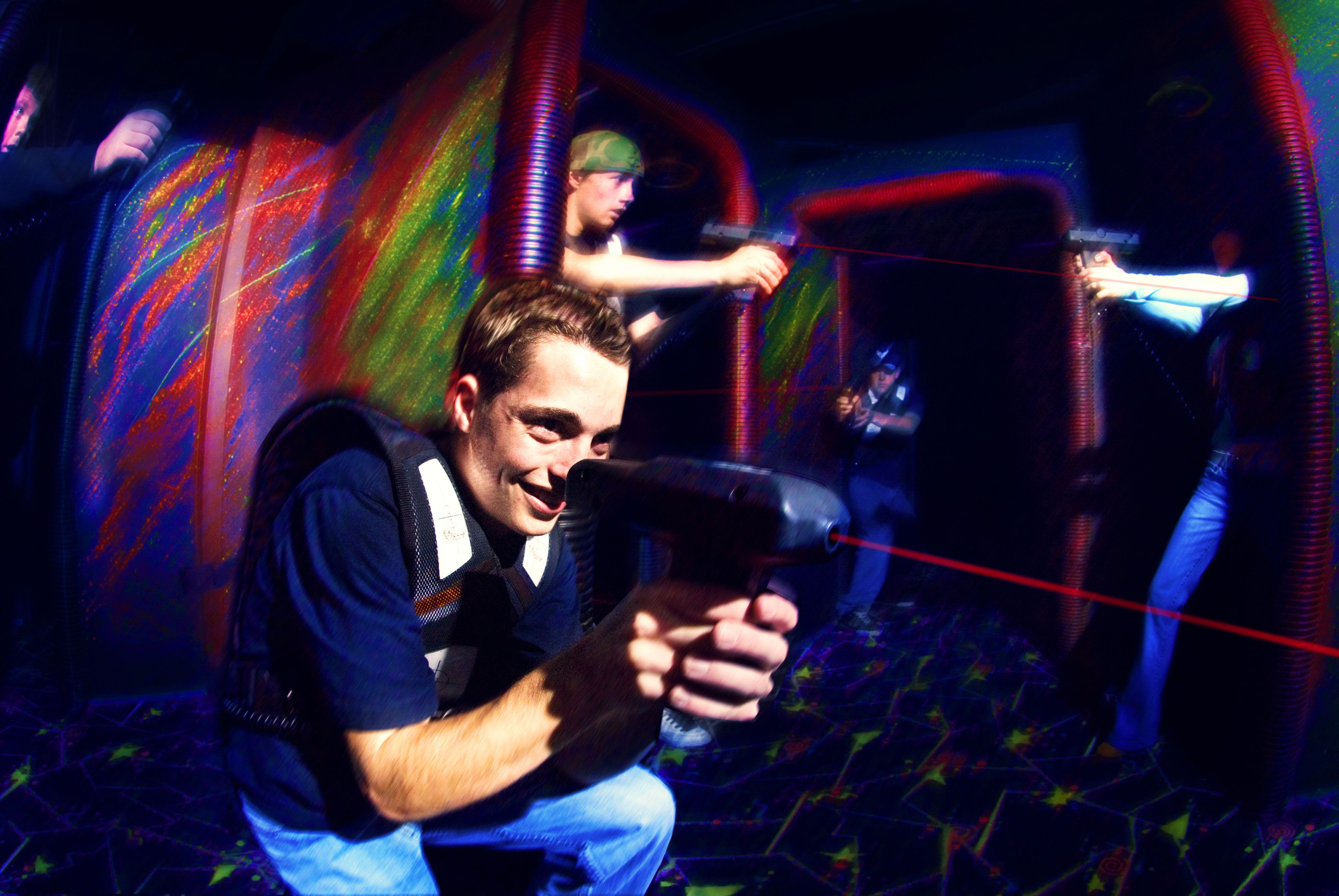 A person holding a device in a dark room with colorful patterns on the walls.