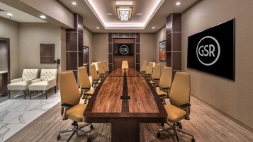 Un salón de conferencias con una larga mesa de madera, sillas color beige y el logotipo de GSR en la pared.