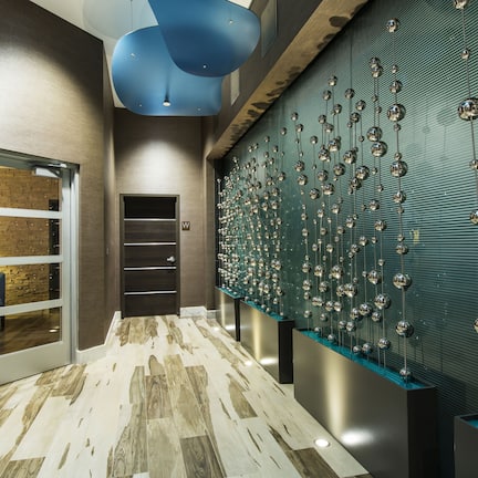 A modern hallway with a treatment lounge, a patterned wall, and a floor with a mix of wood and stone tiles.
