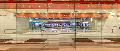 A modern interior with glass partitions, a central seating area, and a ceiling with a perforated design.
