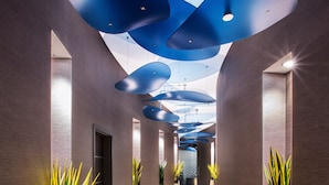 Un pasillo moderno con piso estampado, plantas en macetas y luces de techo azules.