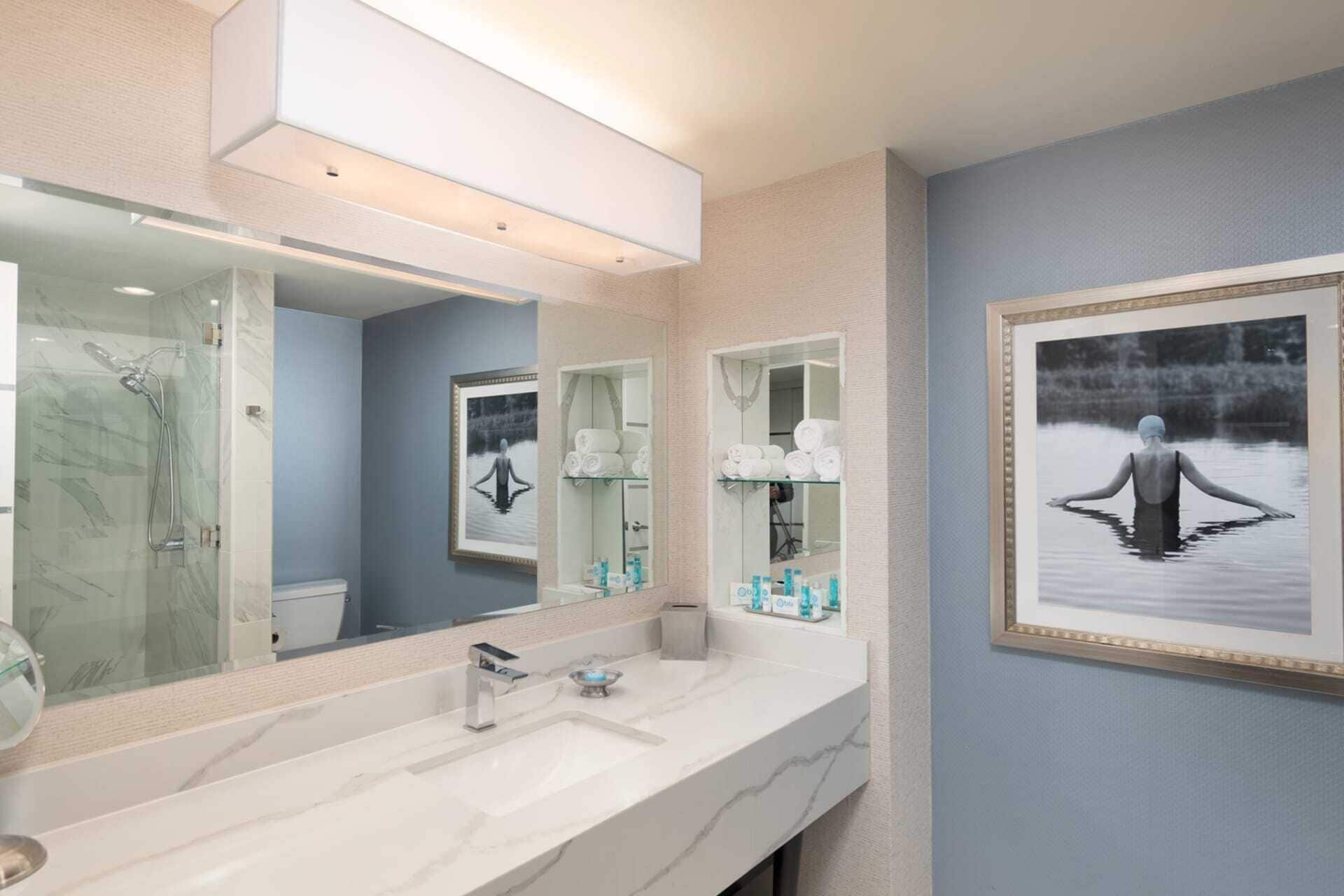 A modern bathroom with a large mirror, a shower, and a sink.
