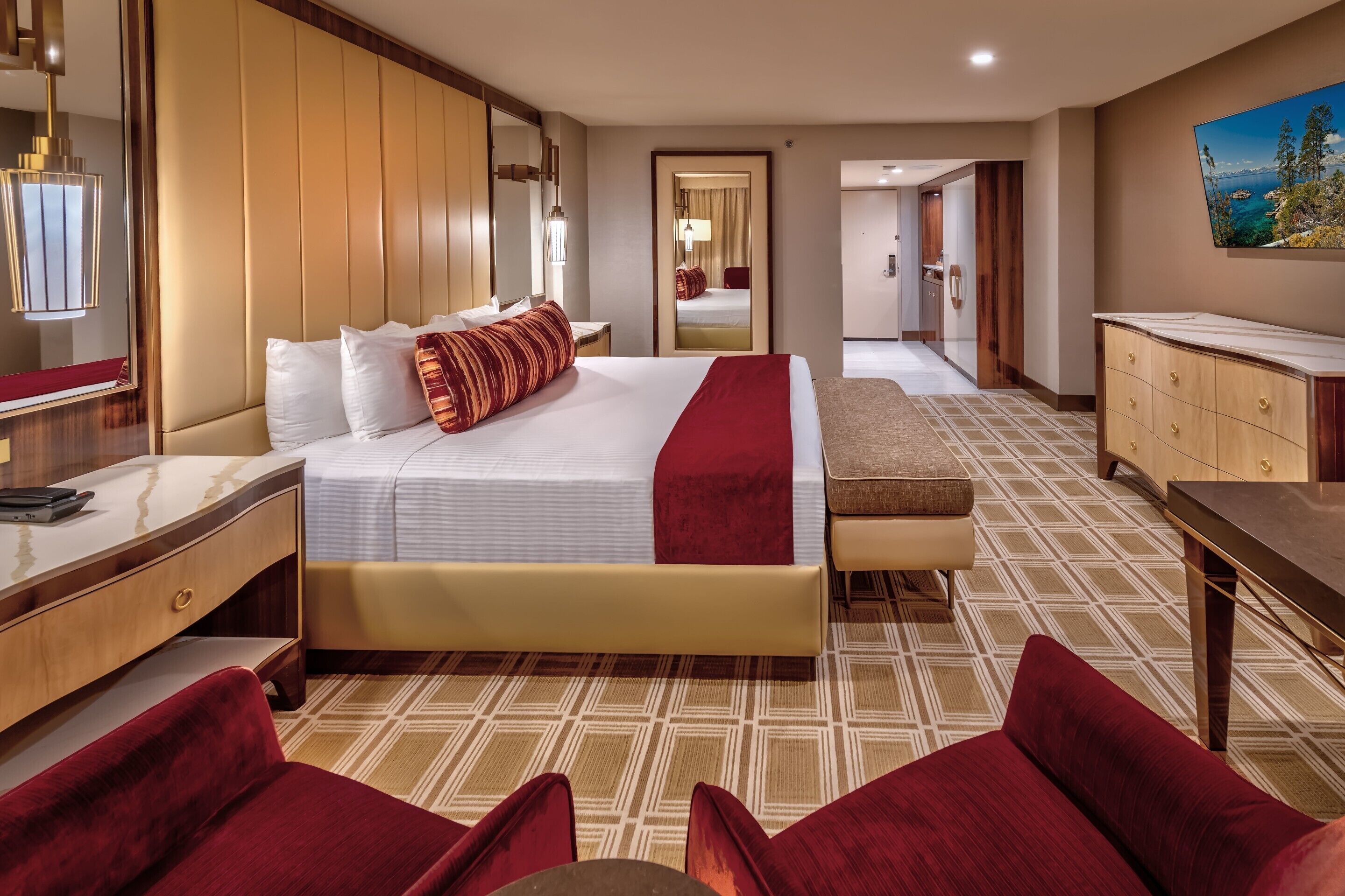 A hotel room with a large bed, a desk, a chair, a dresser, and a painting on the wall.