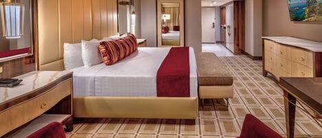 A hotel room with a large bed, a desk, a chair, a dresser, and a painting on the wall.