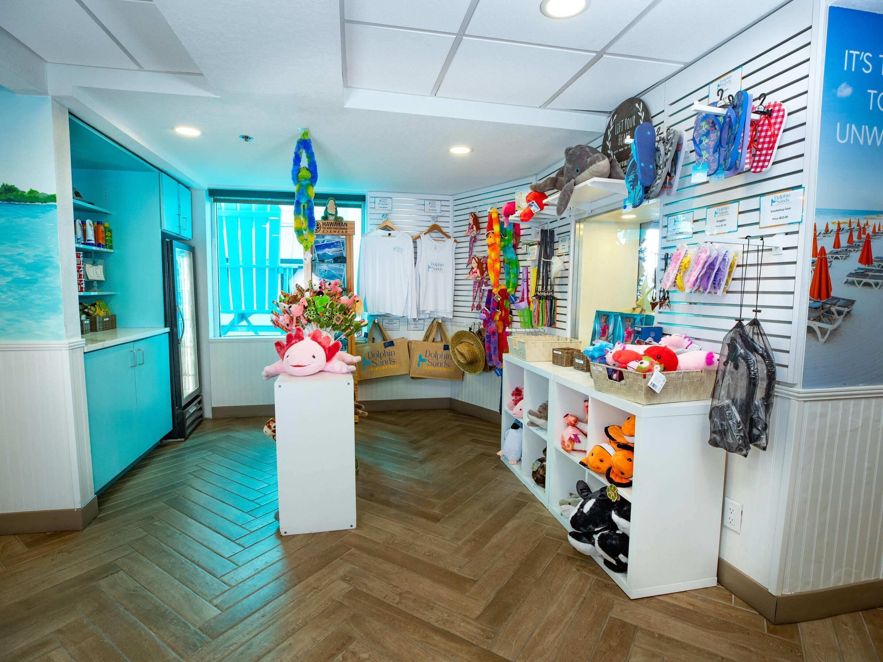 A room with a herringbone floor, a refrigerator, a display of plush toys, and a wall with hanging items.