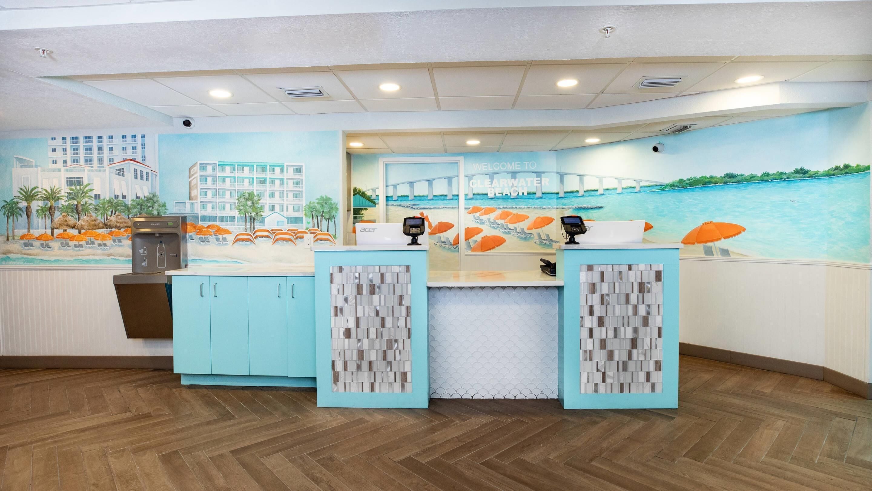 A reception area with a beach mural, a reception desk, and a counter with a cash register.