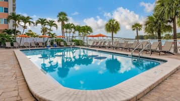 Una piscina al aire libre, sombrillas, sillones reclinables de piscina