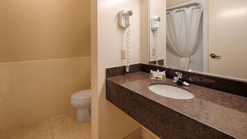 A bathroom with a sink, mirror, and hairdryer mounted on the wall.