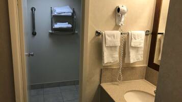 Un baño con inodoro, lavamanos, toallero y secador de pelo.