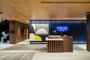 A modern reception desk with a digital sign displaying 'Voco by IHG'. - voco Bangkok Surawong by IHG (Bangkok)