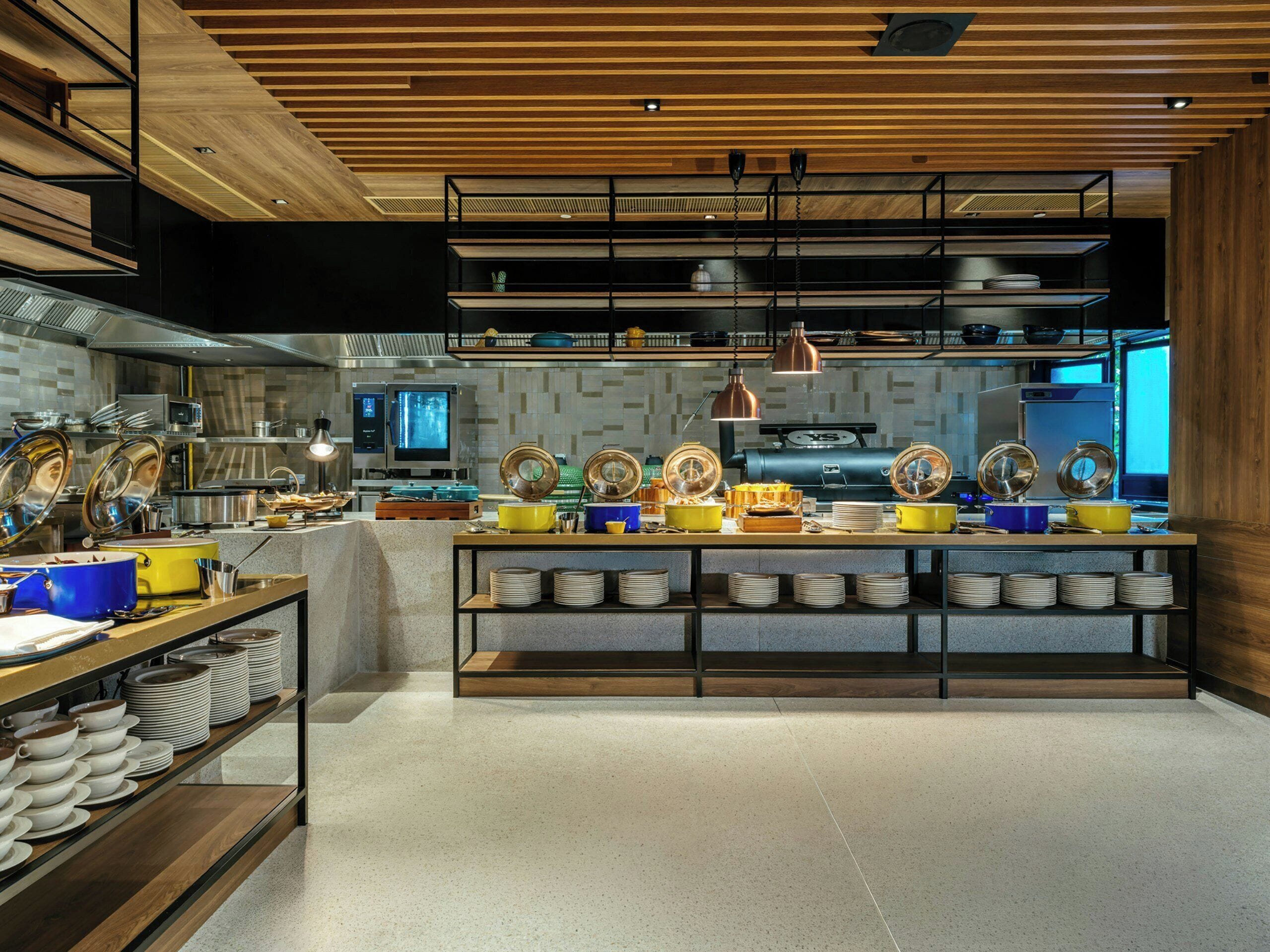 A modern kitchen with wooden beams, stainless steel appliances, and a variety of cookware on display.