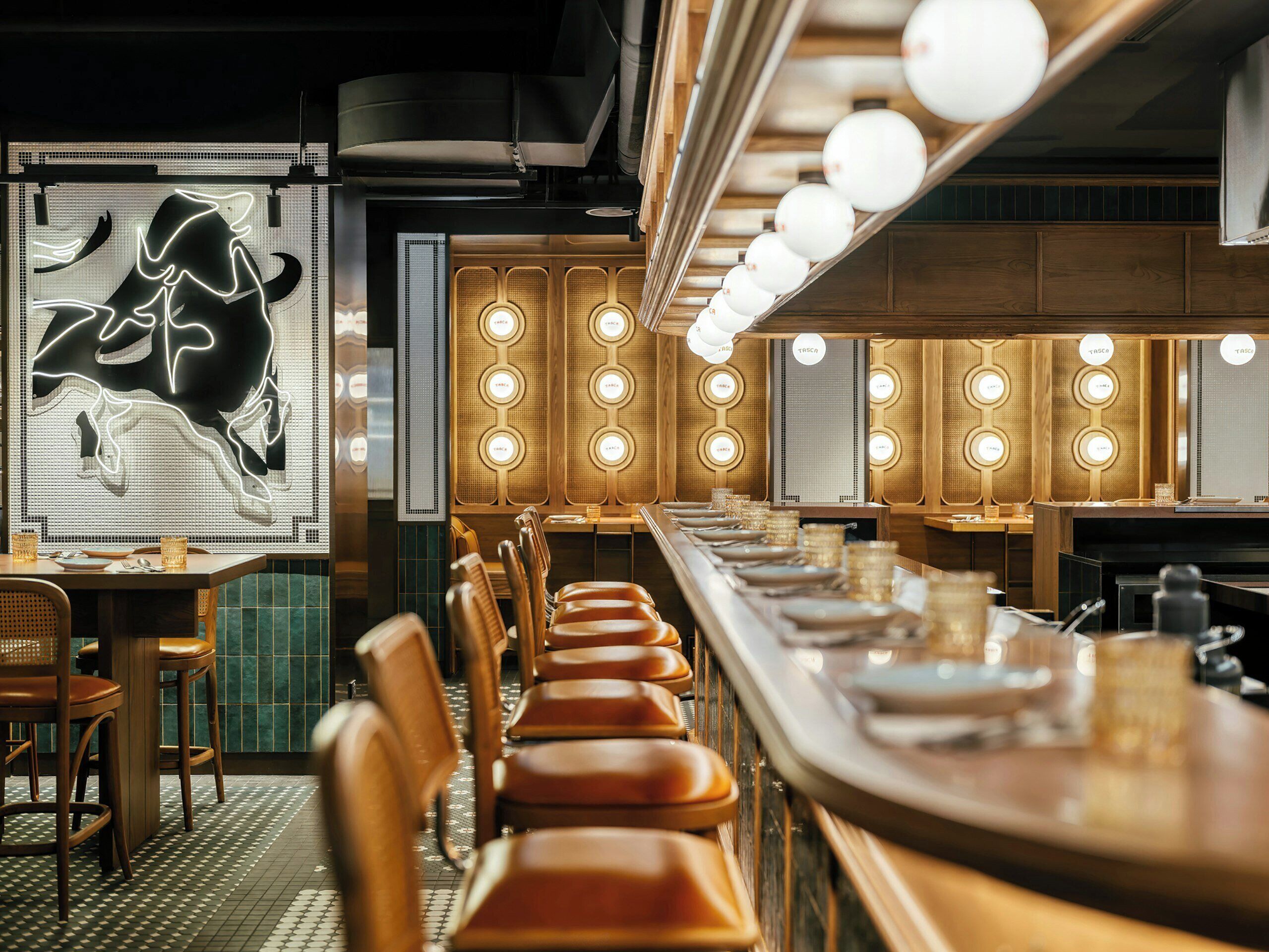 Ein Restaurantinneres mit einer langen Theke, mehreren Tischen und Stühlen.