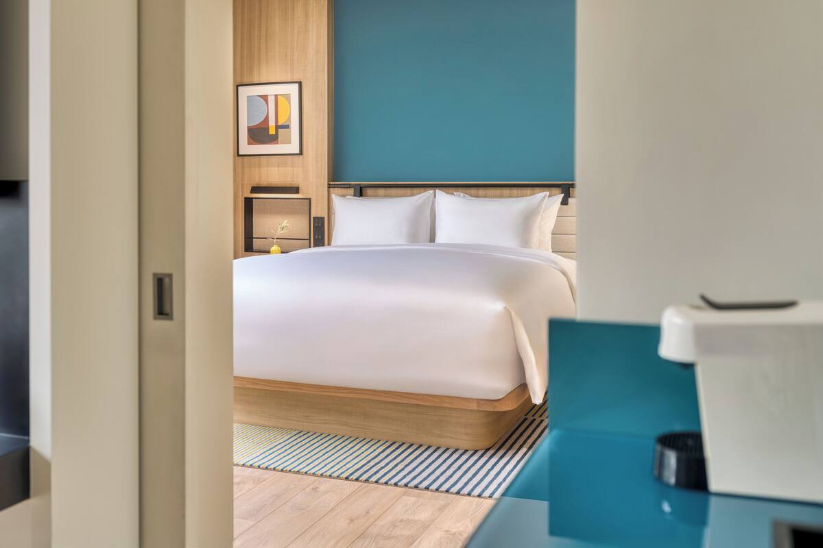 Une chambre d’hôtel équipée d’un lit, d’un bureau et d’un téléviseur fixé au mur.