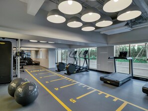 Un gimnasio con cintas de correr, elípticas y equipo de levantamiento de pesas.