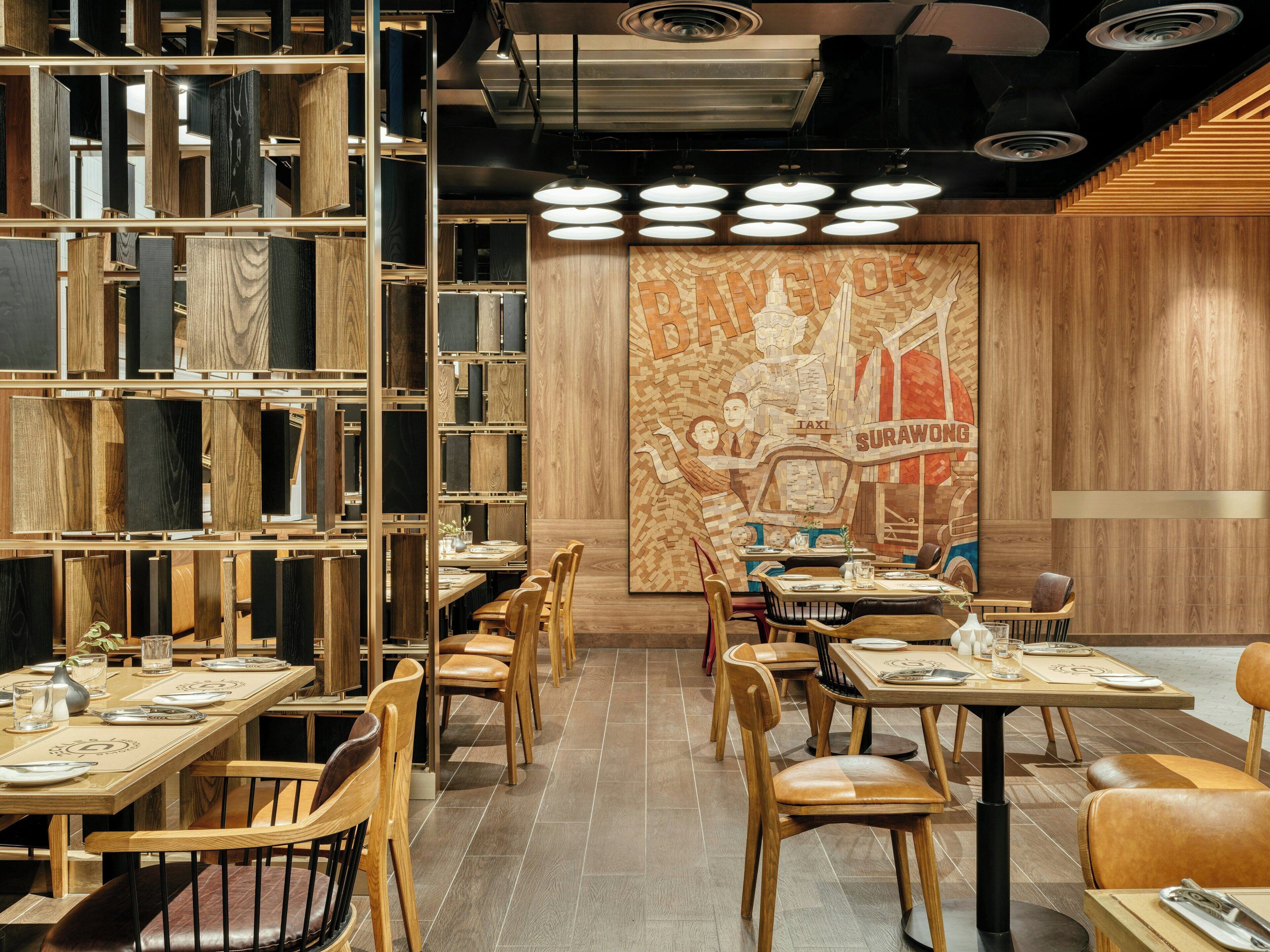 A restaurant interior with wooden furniture, a mural, and a ceiling with circular lights.
