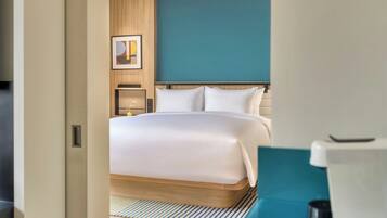 A hotel room with a bed, a bedside table, a lamp, and a wall-mounted artwork.