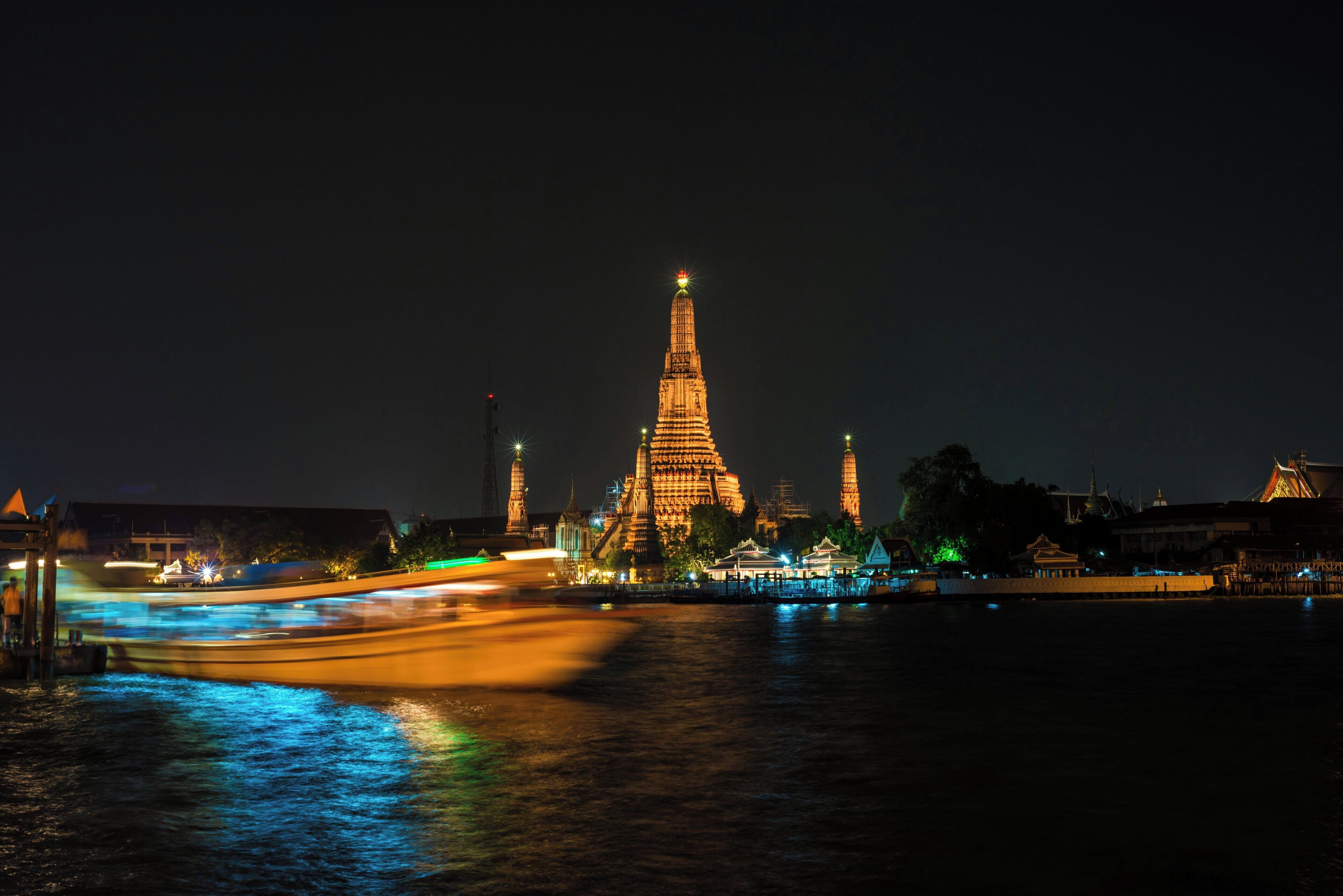 A night view of a historic temple complex with illuminated structures and a river reflecting lights.