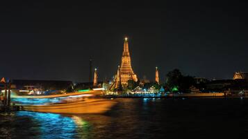 A night view of a historic temple complex with illuminated structures and a river reflecting lights.